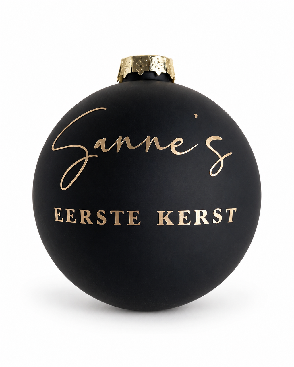 Matzwarte glazen kerstbal met een goudkleurige naam, tekst Eerste kerst en jaartal, los gefotografeerd tegen een lichte achtergrond.