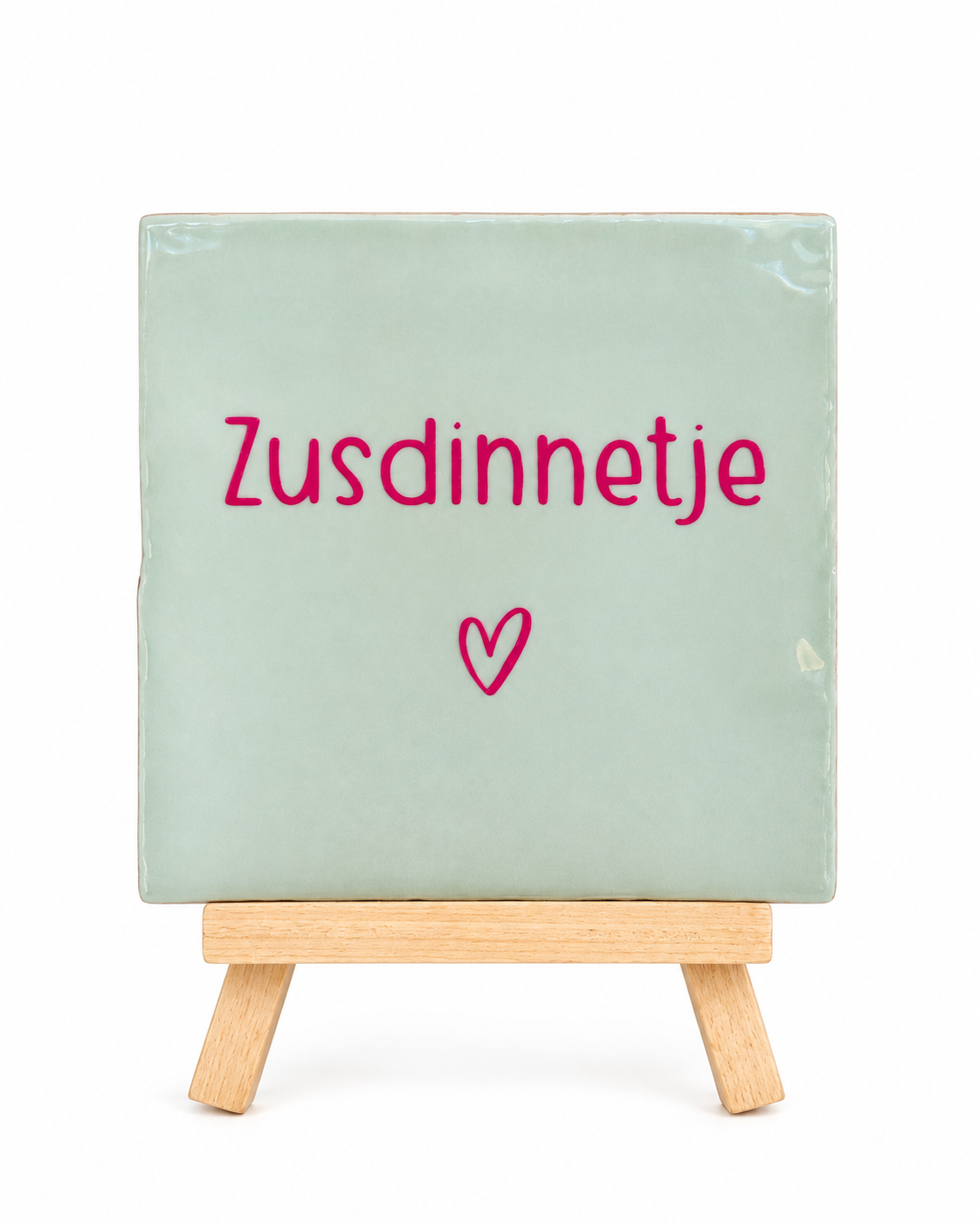 Mintgroen keramieken Zusdinnetje tegeltje met roze opdruk en hartje, op houten standaard tegen een witte achtergrond.